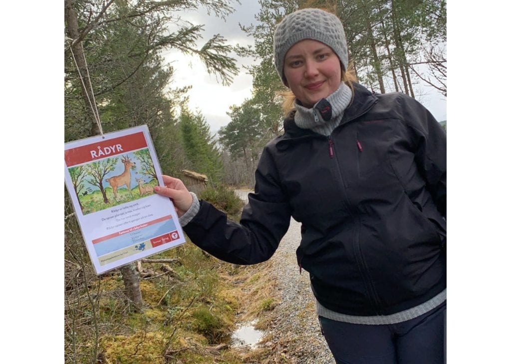 Ann-Iren Aas viser fram ein av postane som Barnas turlag Vestnes har hengt opp i Kråkvika friluftsområde.