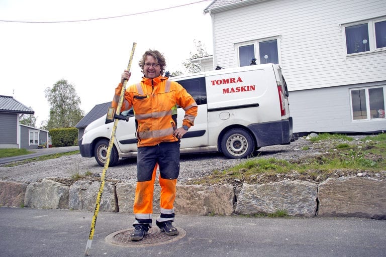 Mann i anleggsklede framfor bil frå Tomra Maskin.